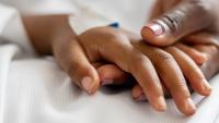 Close-up on a mother holding her daughter's hand at the hospital.
